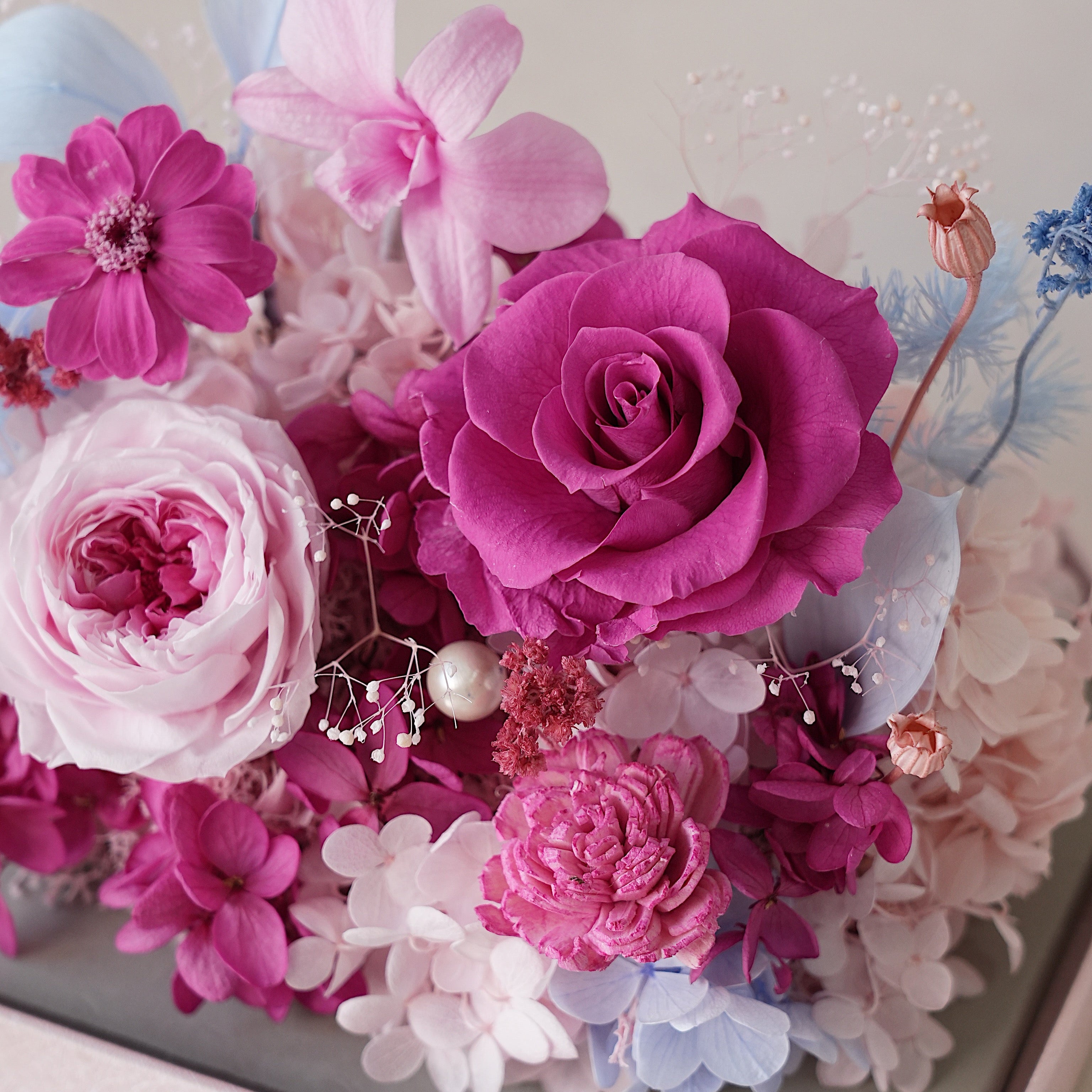 Colorful flower arrangement with pink and purple flowers on a light background