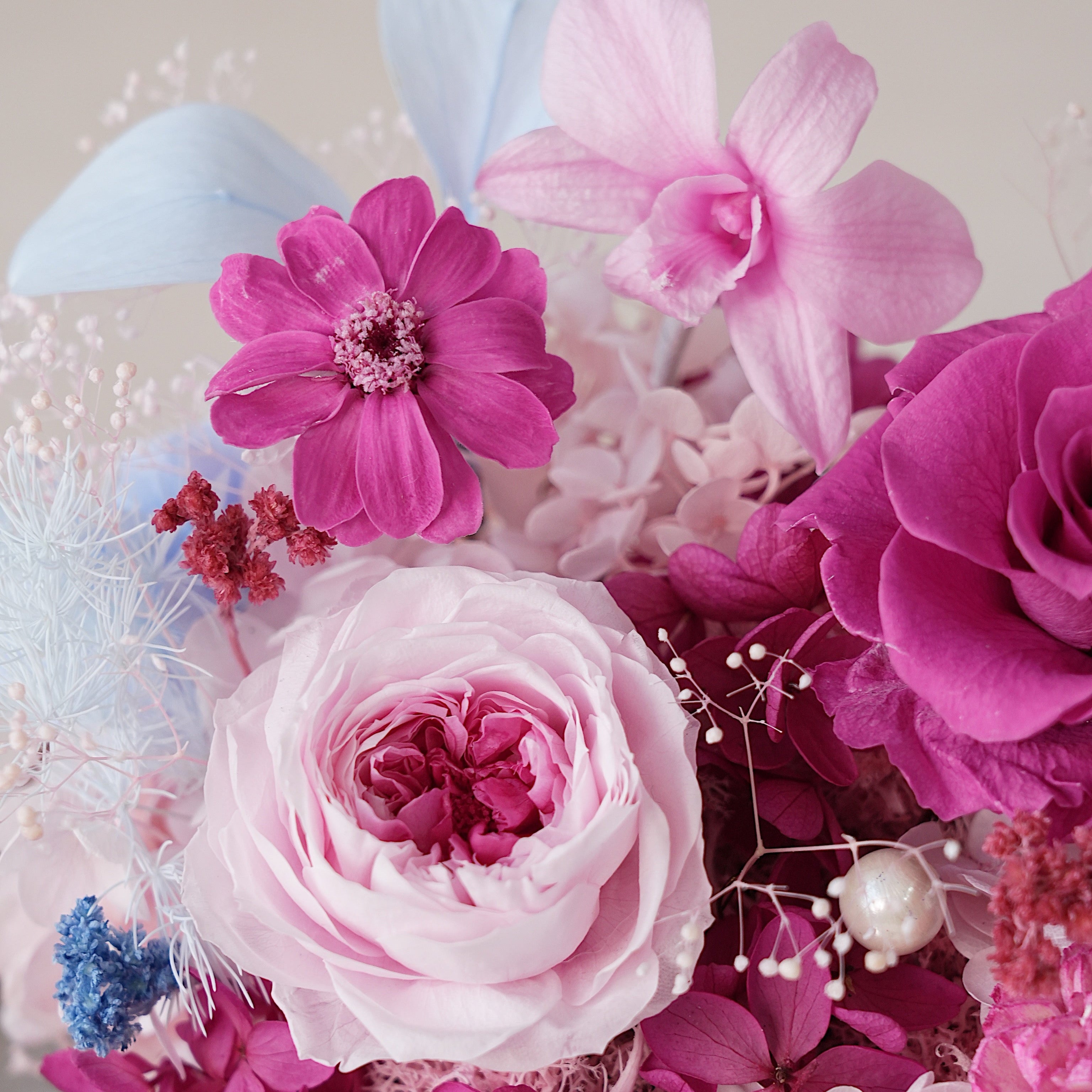 Close-up of a bouquet with pink, purple, and white flowers on a light background