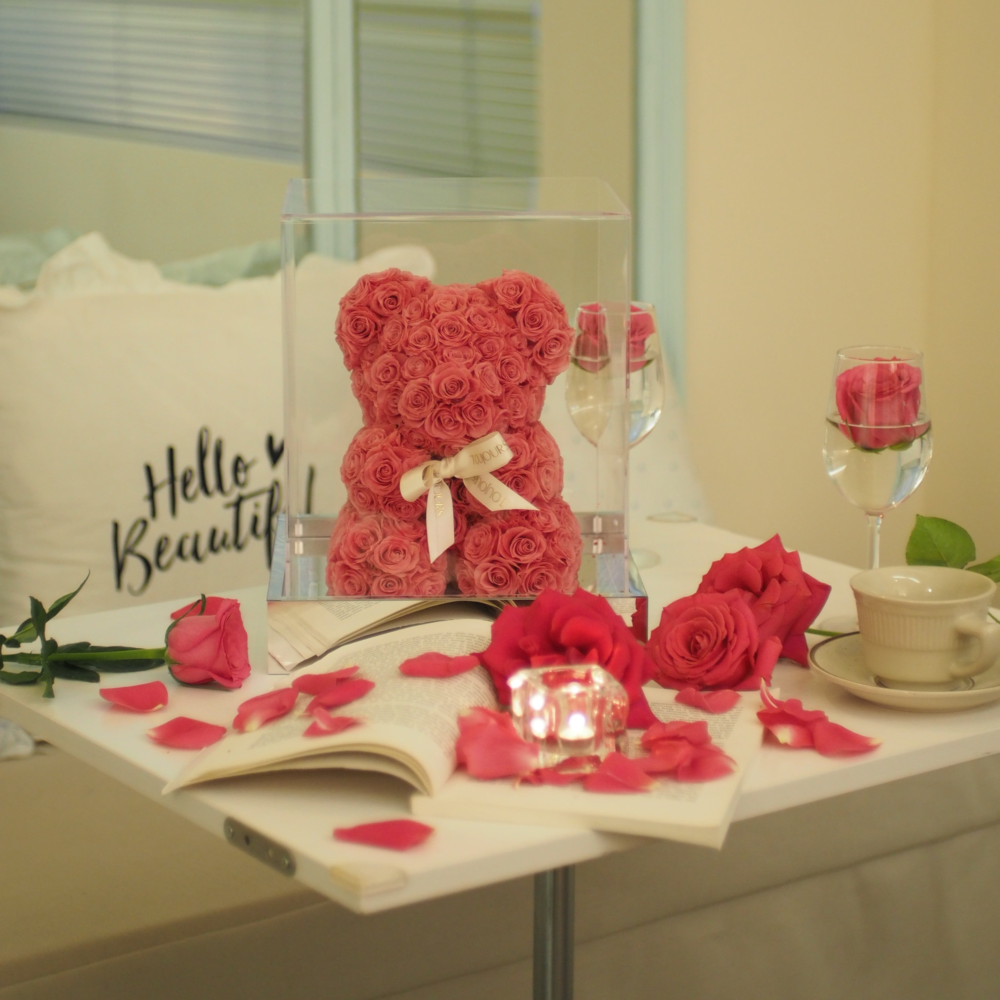 Decorative item with red roses shaped like a bear and a heart, placed on a surface.