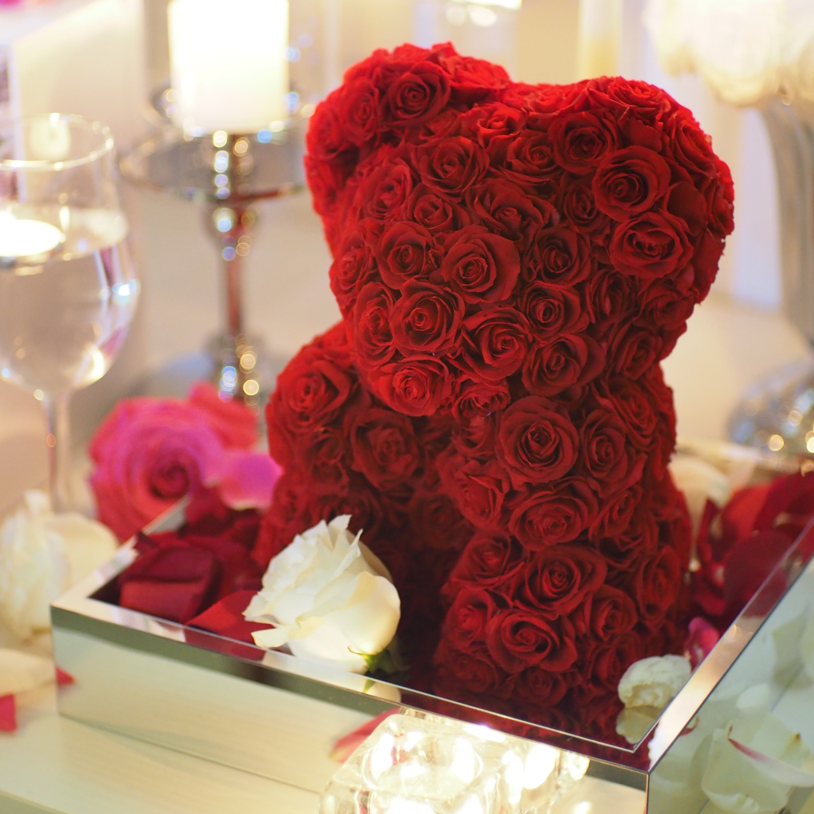 Red rose teddy bear with a white rose on a blurred background