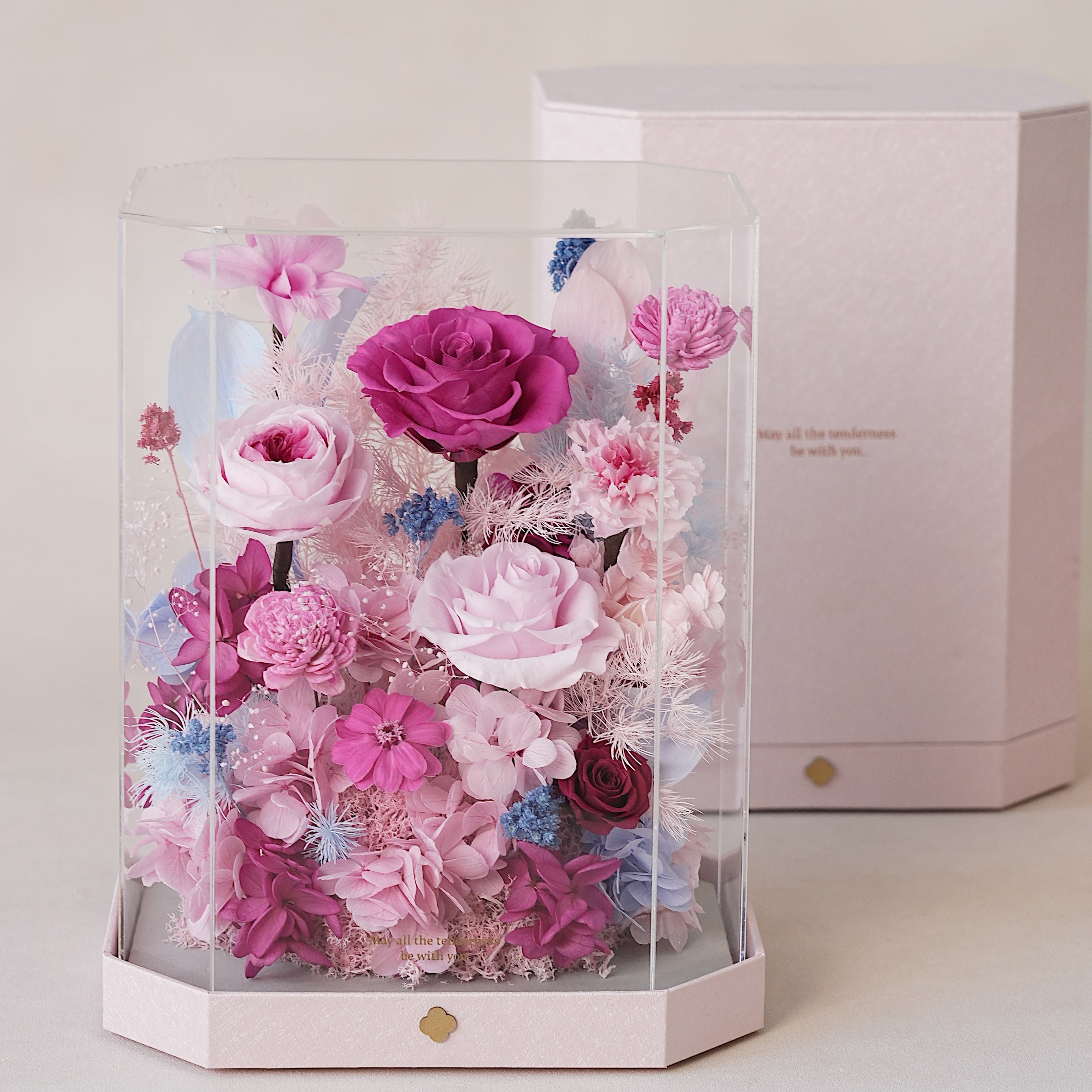 Hexagonal clear box with preserved pink and purple flowers on a light background
