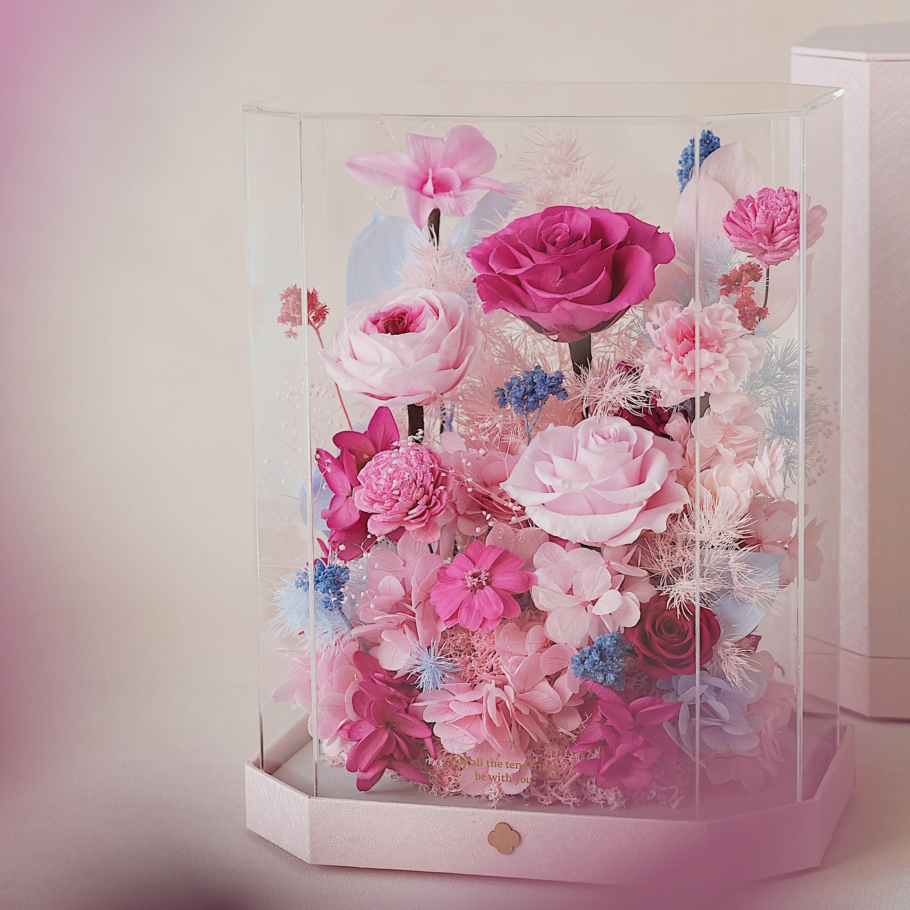 Hexagonal clear display box filled with pink and blue flowers on a light background