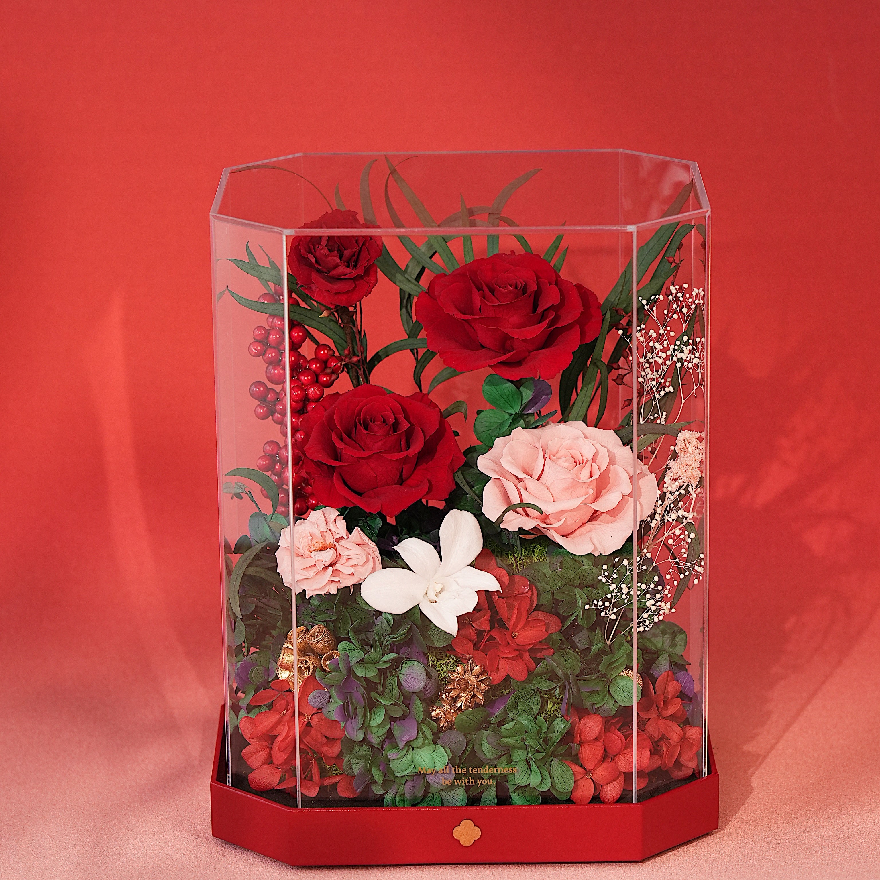 Hexagonal glass display case with red, pink, and white flowers on a red background