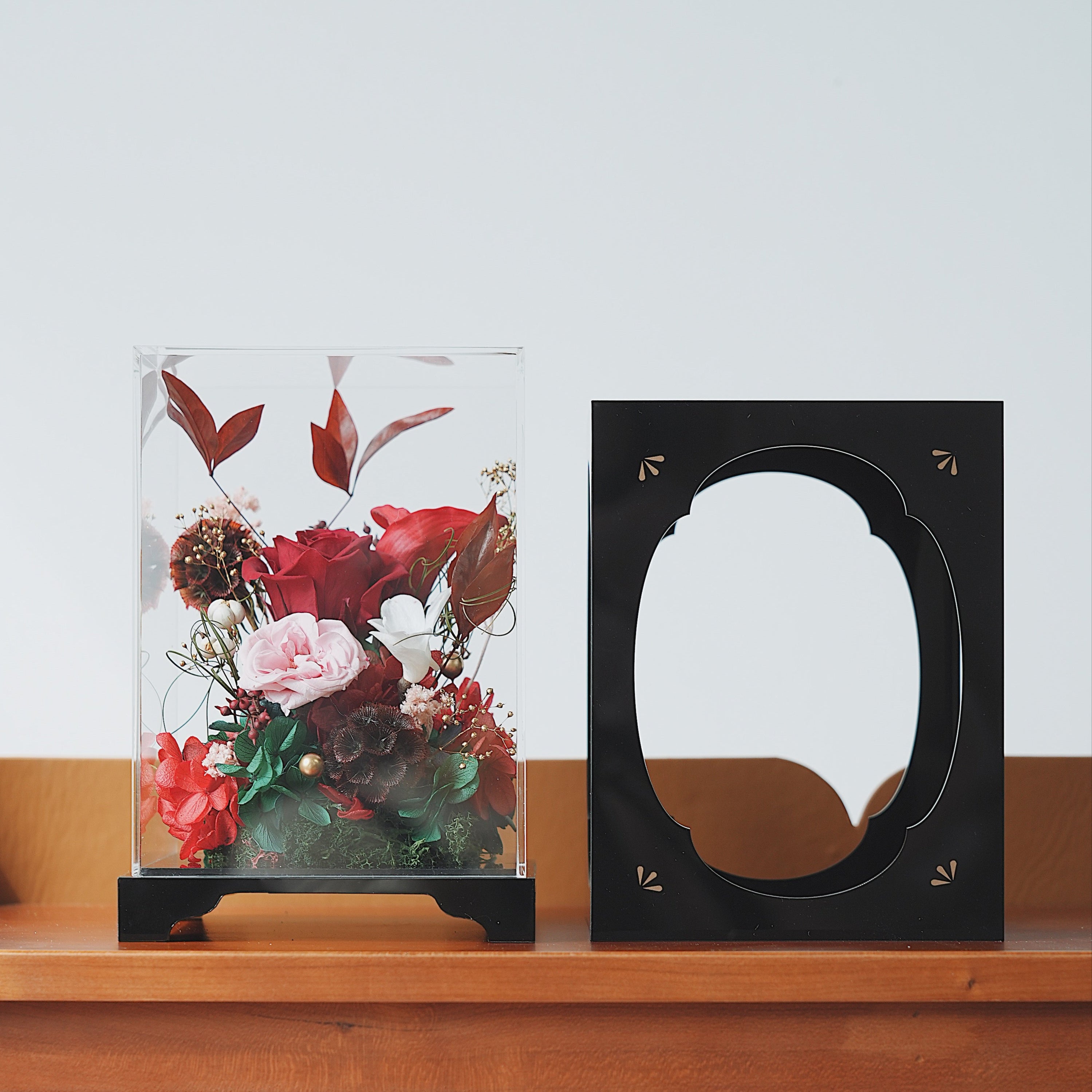 Decorative Acrylic box with floral arrangement and black frame on wooden shelf