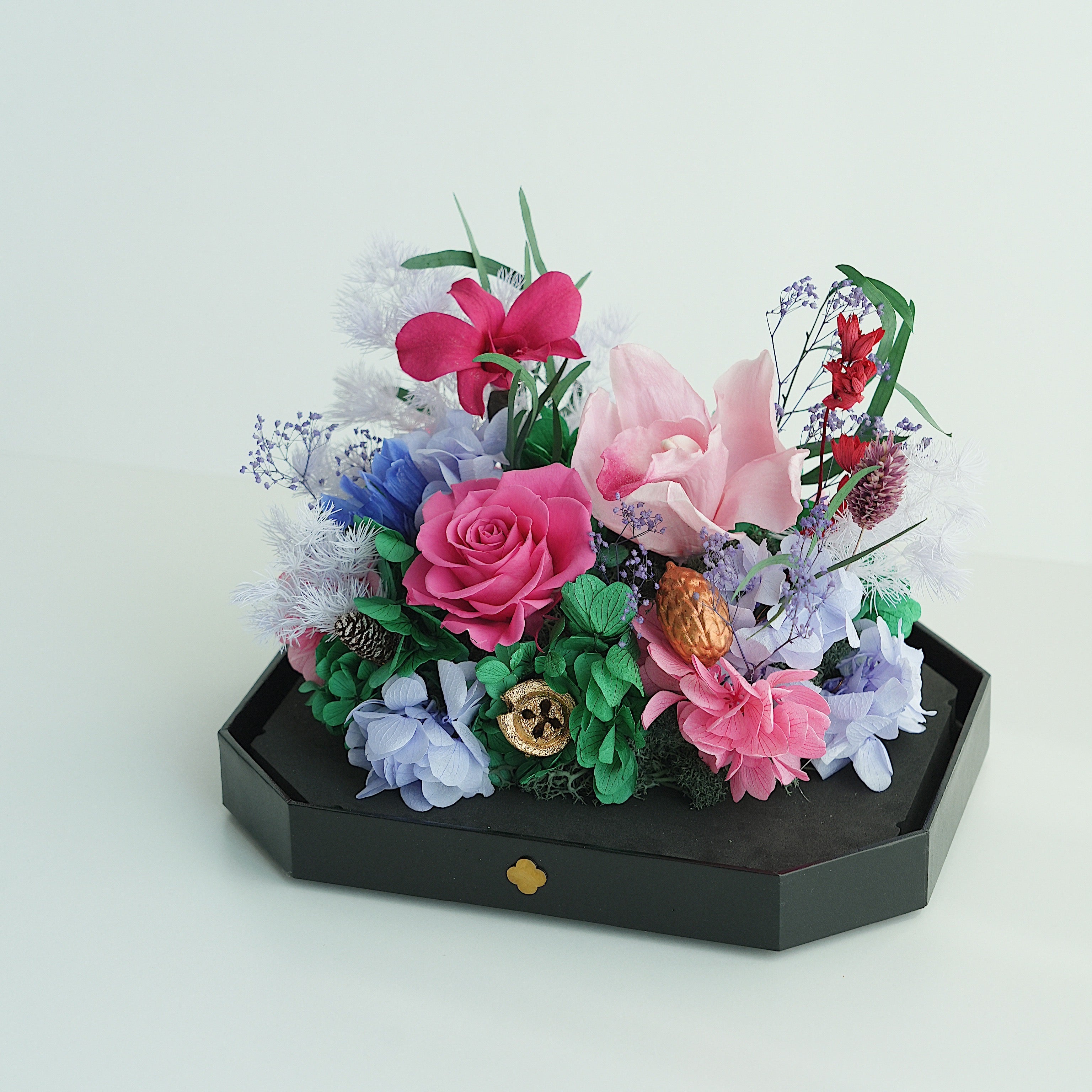 Colorful flower arrangement on a black stand against a light gray background