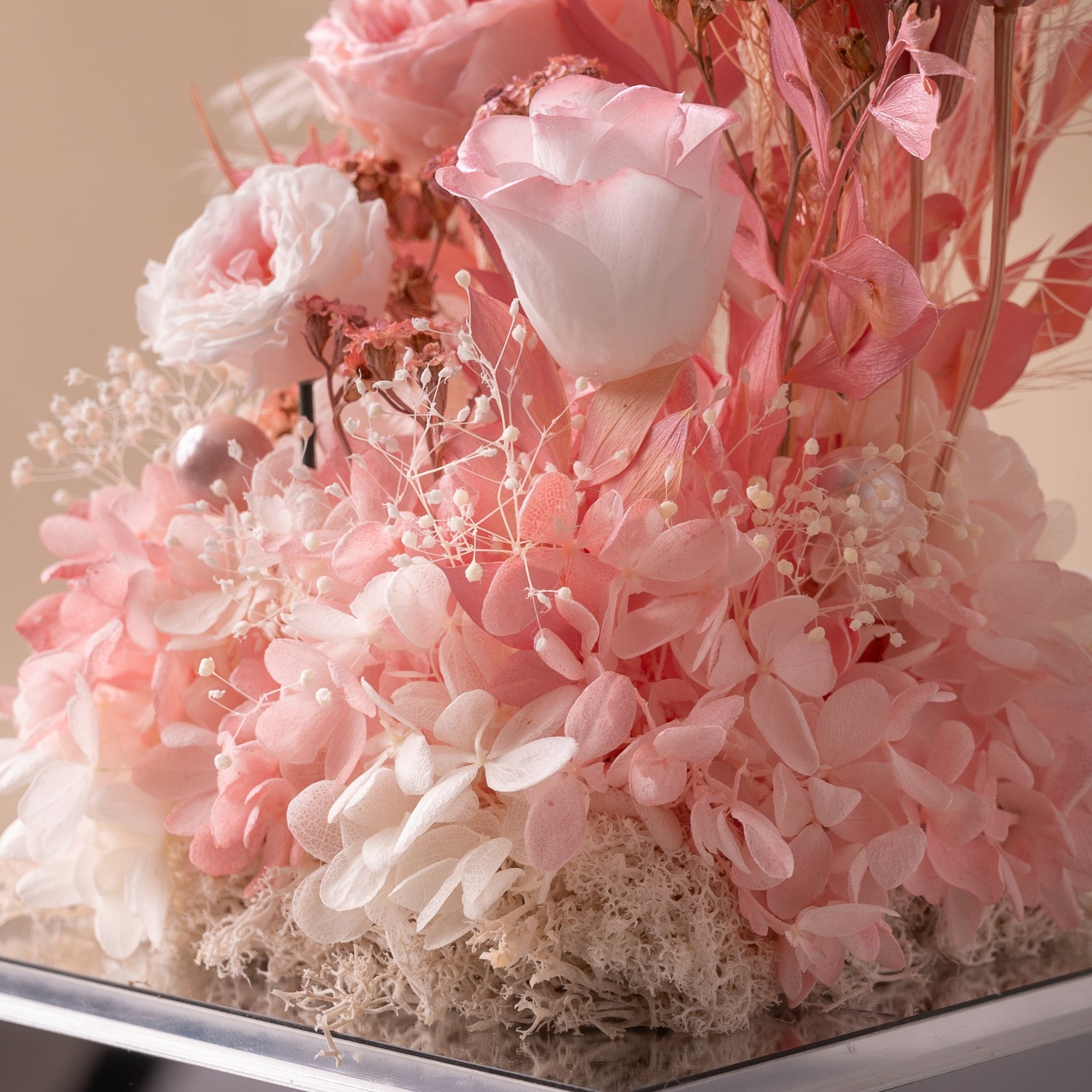 Decorative floral arrangement with pink and white flowers on a reflective surface.