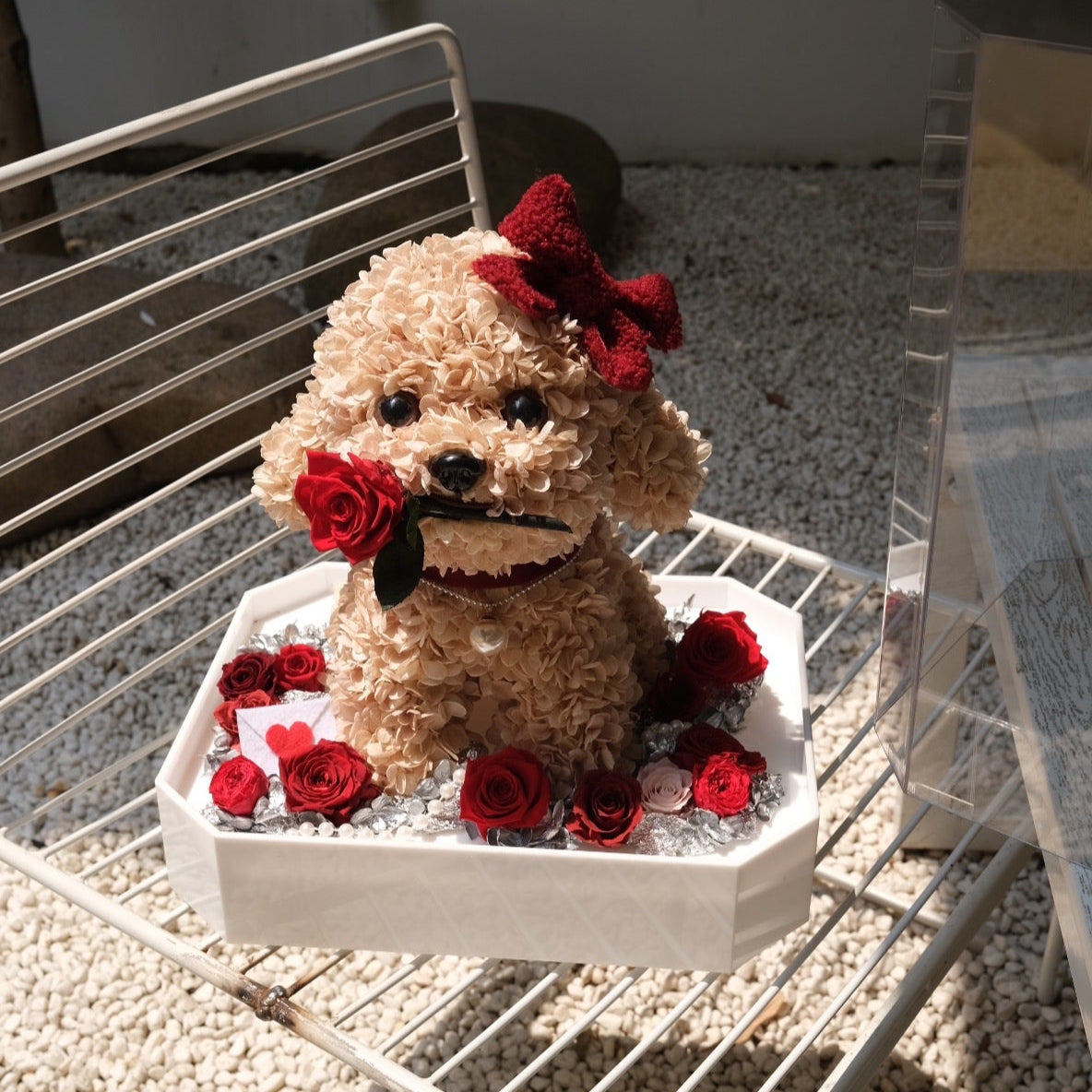 Floral Doggy Brown Poodle  with red roses on a white stand outdoors