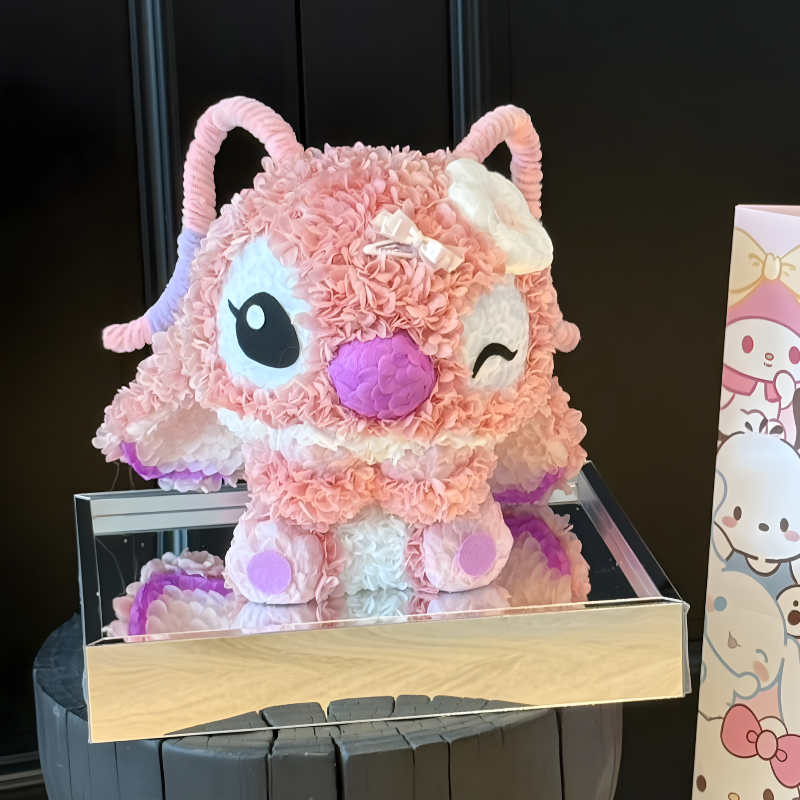 Pink Angel with a purple nose on a stand next to a cartoon character-themed box.
