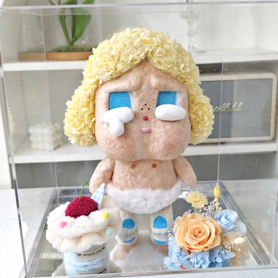 Flower Crybaby-baby blonde with blonde hair and blue eyes in a display case with flowers and a cake.