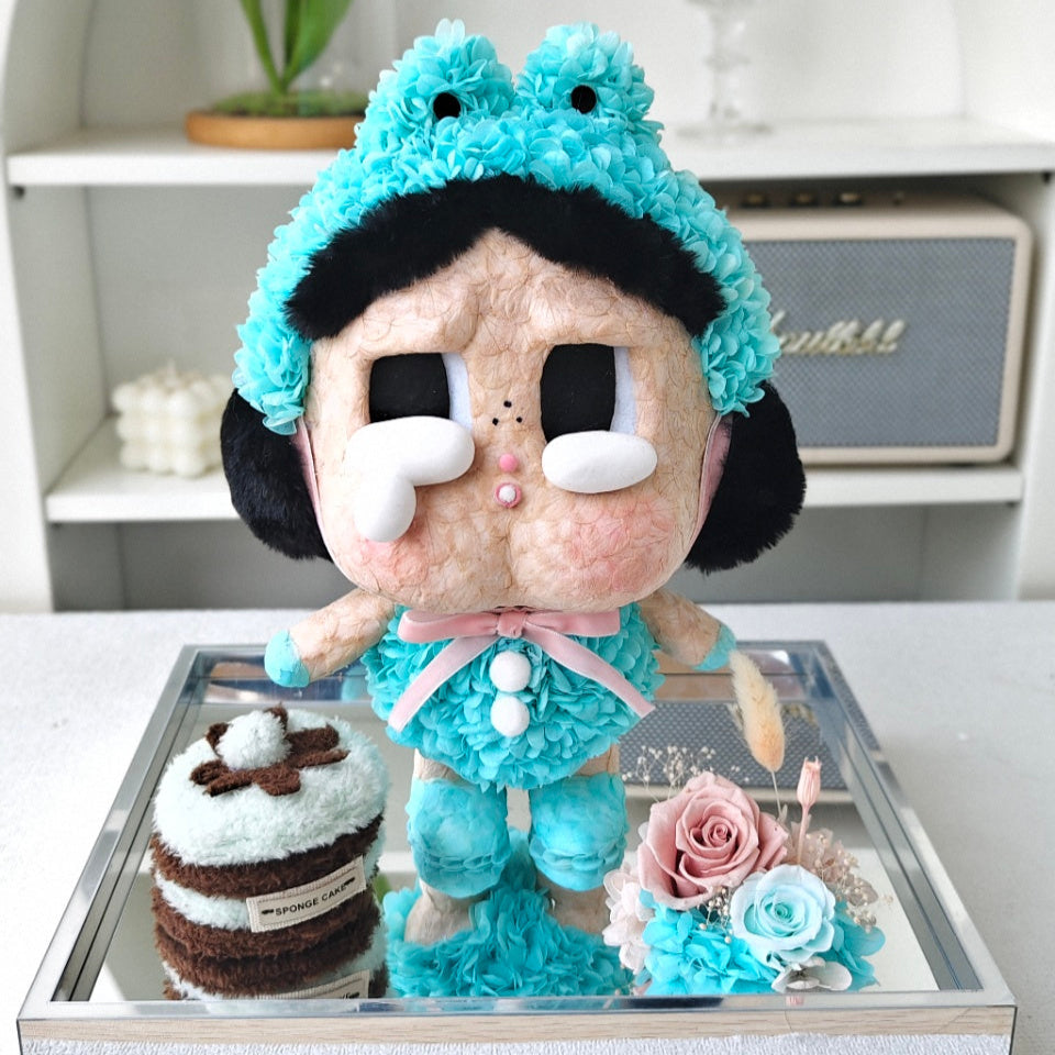 Flower Crybaby-what a frog with blue hair and outfit on a reflective surface with decorative items.