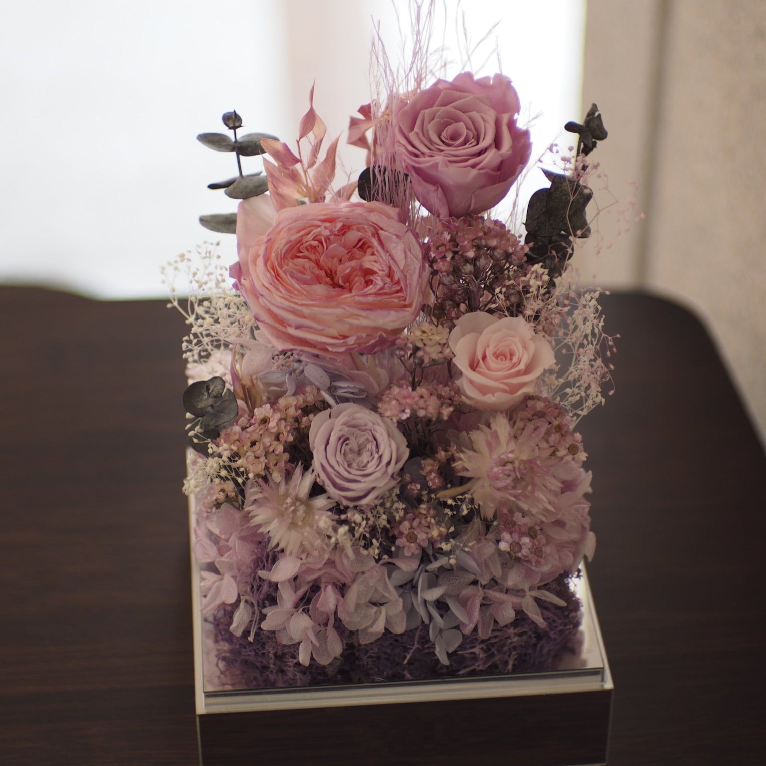 Decorative floral arrangement on a reflective surface with a blurred background