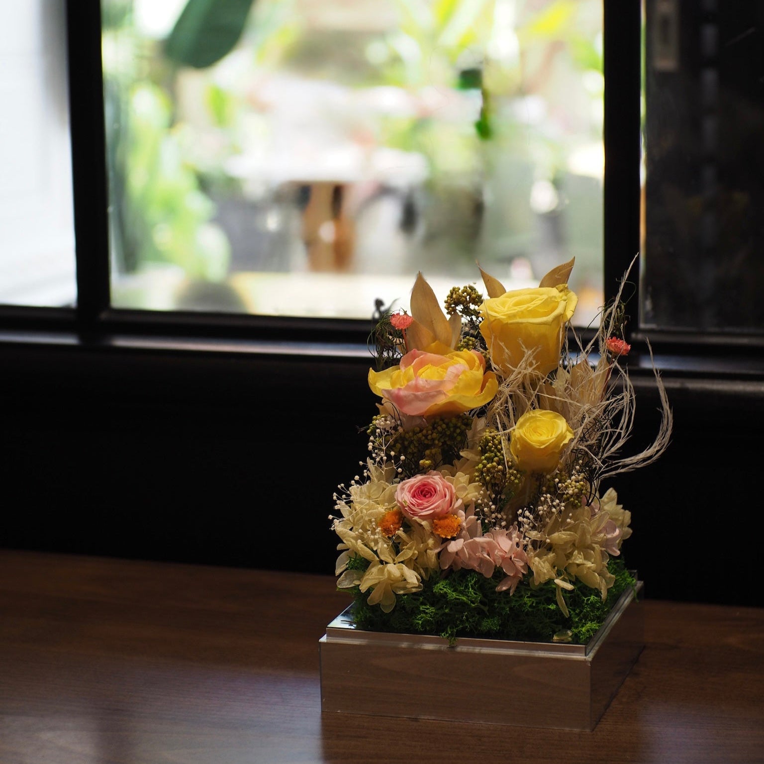 Floral arrangement in a pot on a wooden floor with a blurred background