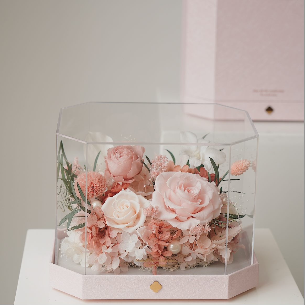 Hexagonal glass container with pink and white flowers on a light background