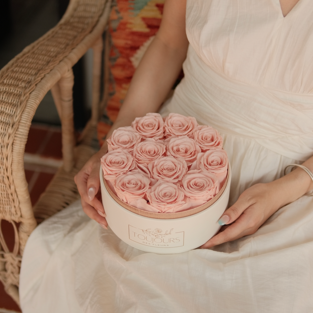 Person holding a round box of pink roses 