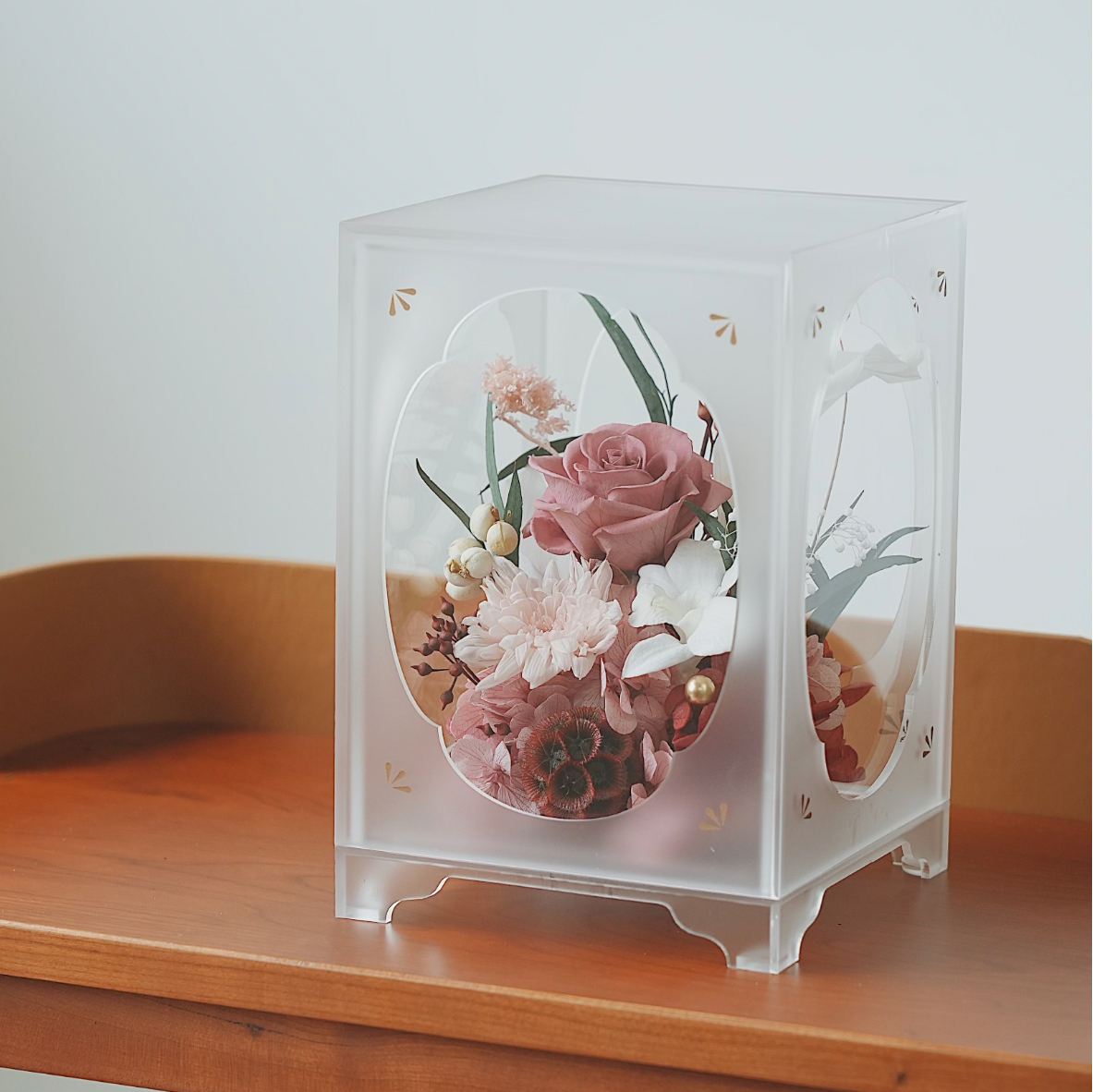 Transparent cube with preserved flowers on a wooden surface