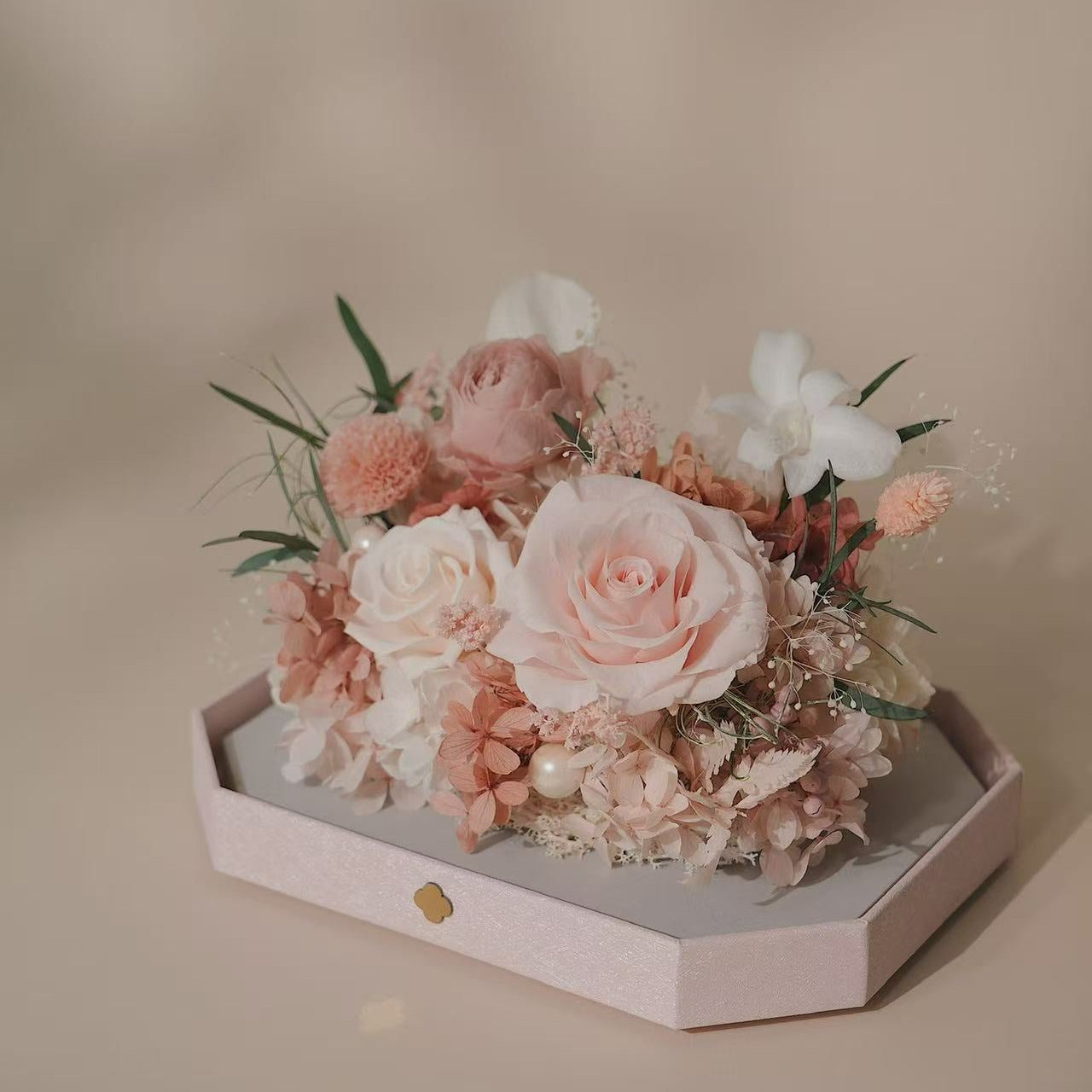 Bouquet of pink and white flowers on a hexagonal white stand against a beige background