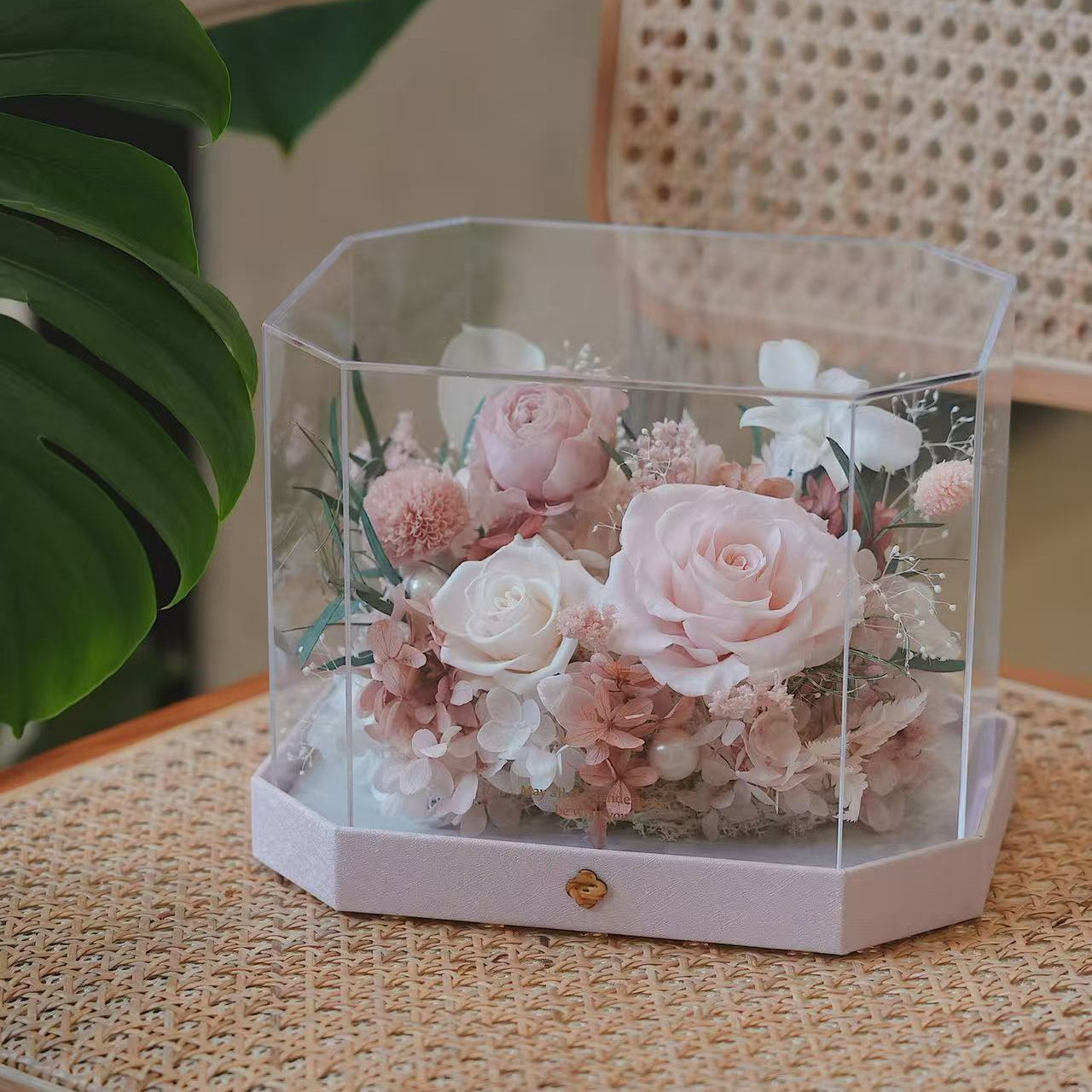 Hexagonal transparent box with pink and white flowers on a textured surface