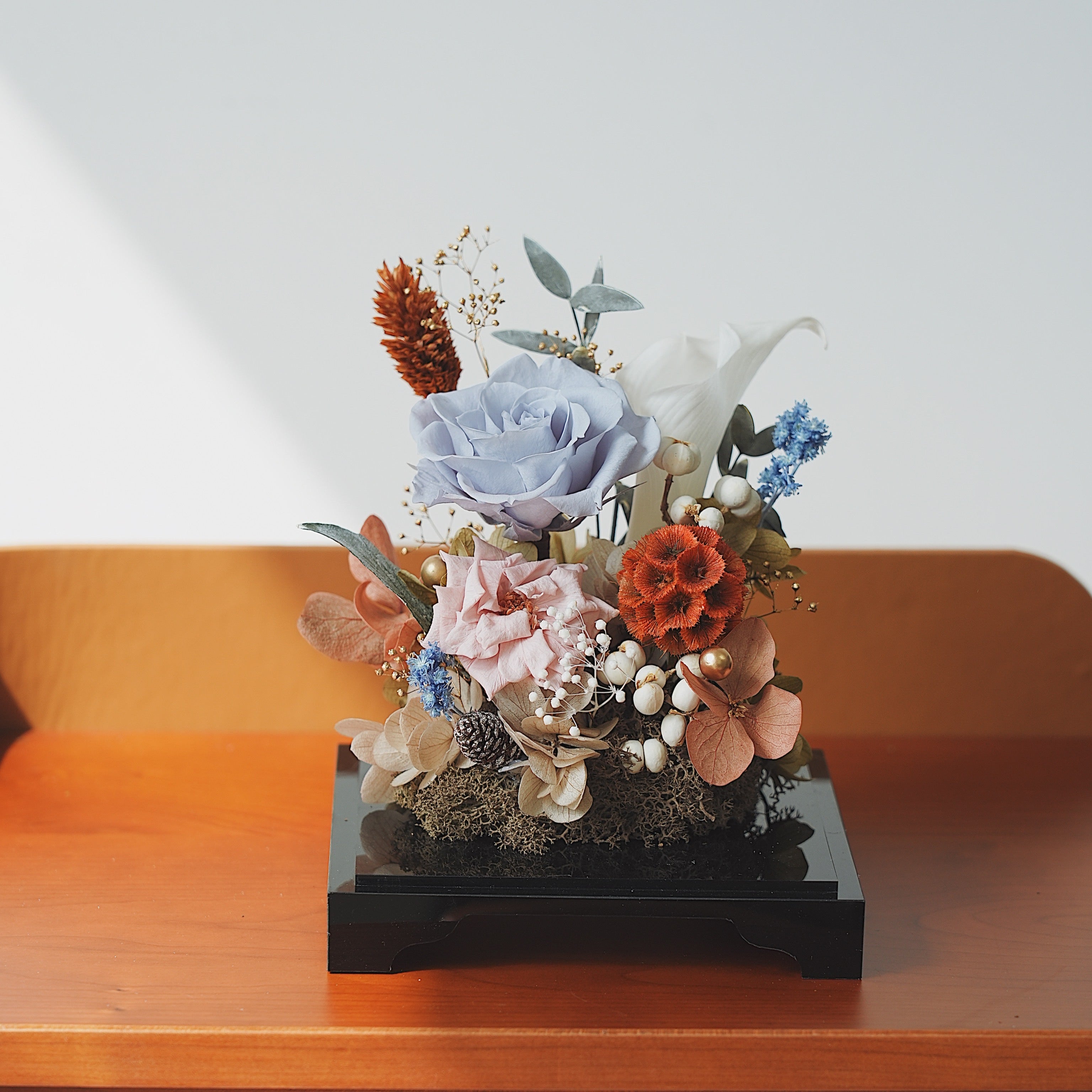Decorative floral arrangement on a wooden surface with a white background