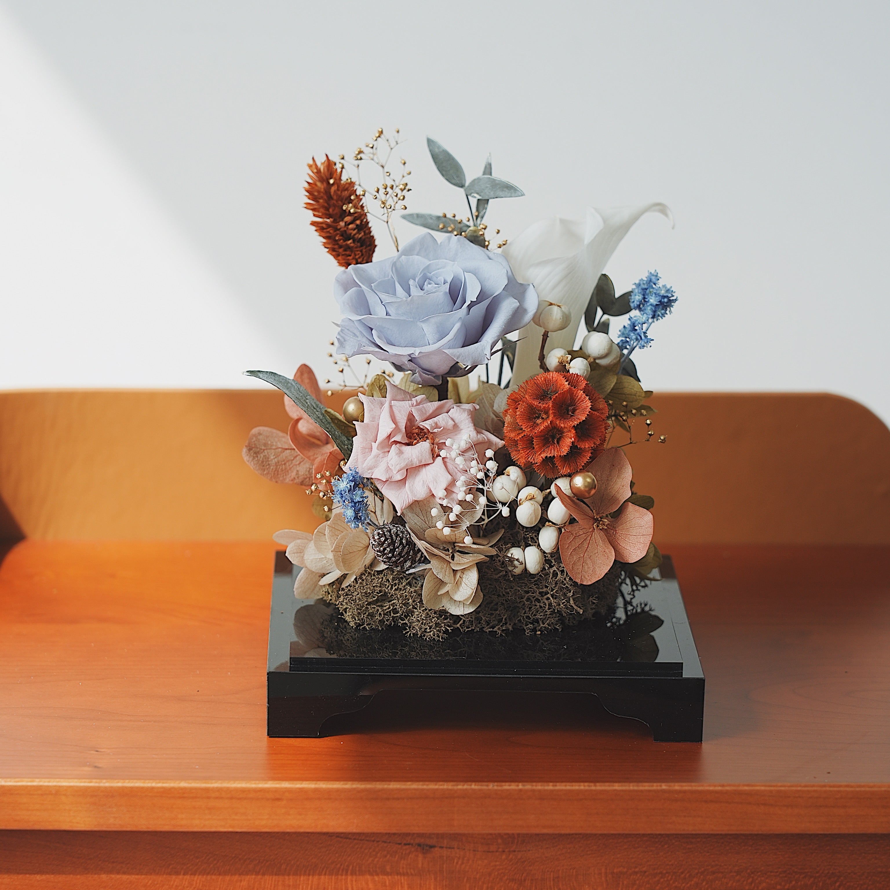 Decorative floral arrangement on a wooden surface with a white background